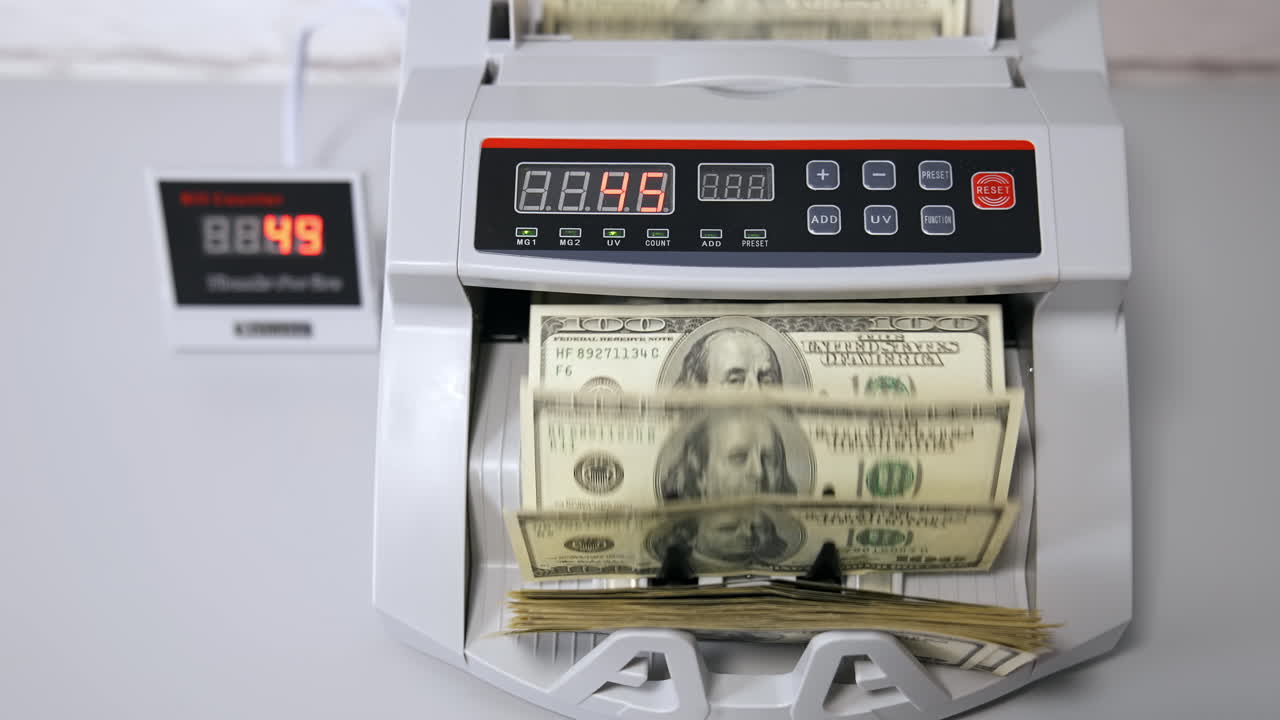 Dollari USA su una macchina contabanconote. Donna che inserisce denaro nella contabanconote.