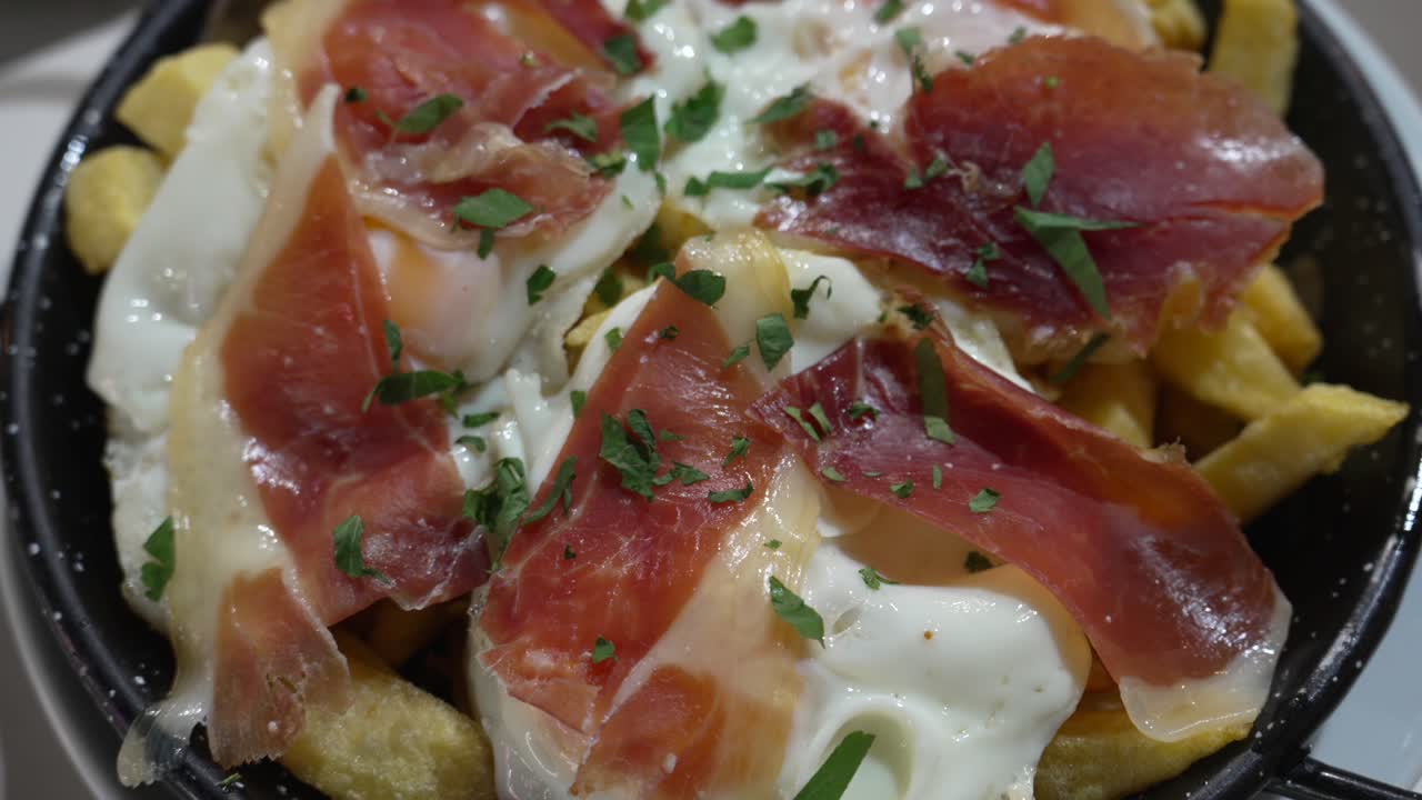 Piatto tradizionale spagnolo huevos rotos con patatine fritte, uova e prosciutto crudo, che mostra la cucina autentica, il comfort food e un'esperienza culinaria locale ideale per concetti di cibo e ristorazione