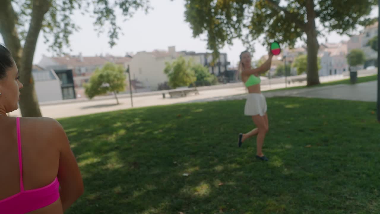 Two women playing frisbee in the park