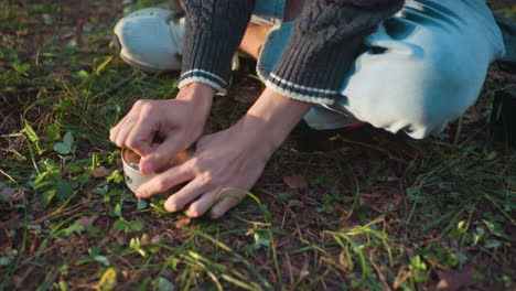 close up of hands trying to open canned food while seated on grass as opener breaks during outdoor meal preparation in natural setting with soft daylight highlighting effort and frustration
