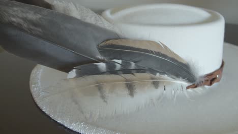 orbit shot of feathers on a white custom beaded wide brim hat