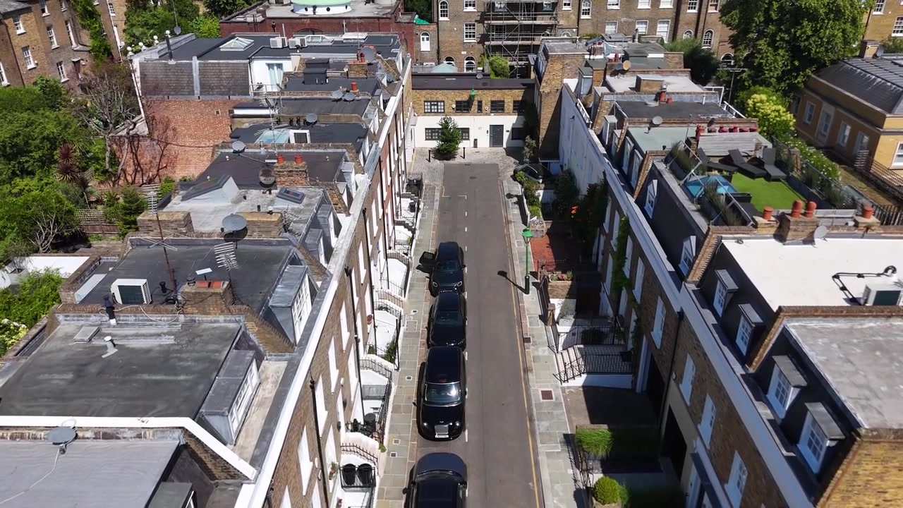 Strada di Mews con case in mattoni e dipinte, con giardini pensili e lucernari, nascosta dietro le case a schiera più grandi di un quartiere prestigioso