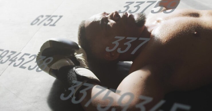 Pugile maschio a riposo dopo il round, sdraiato sul tappeto mentre respira, con una sovrapposizione numerica che traccia le statistiche e i guantoni nelle vicinanze.