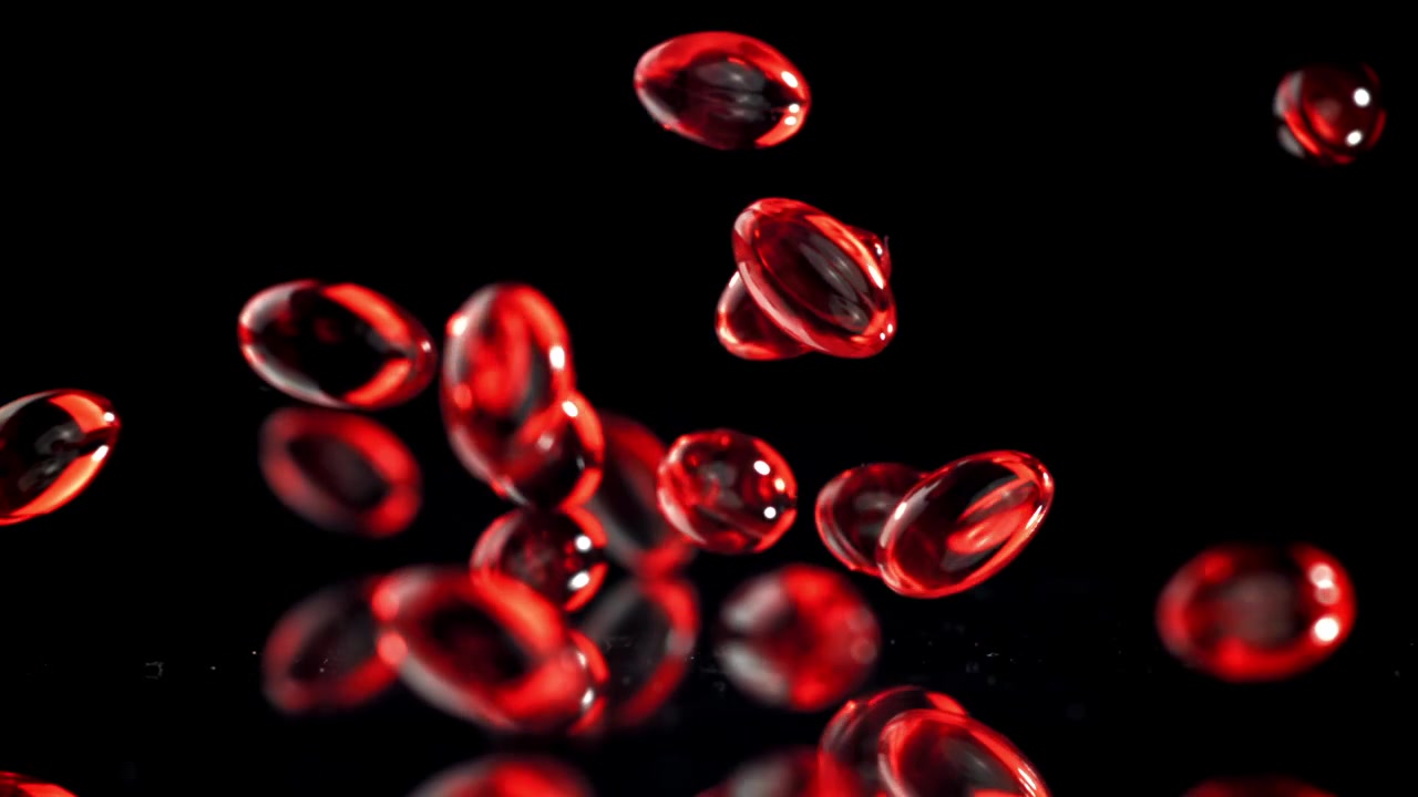 Red Gel Capsules Falling in Slow Motion on Black Background