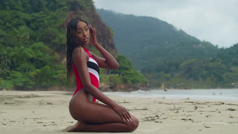 una joven en bikini disfrutando de la playa tropical arrodillada en la arena de la isla de trinidad