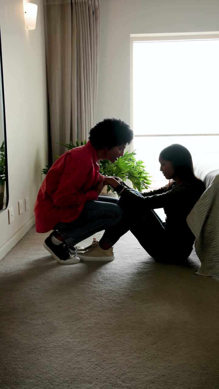 Vertical video: Diverse couple taking hands regaining balance rising embracing in bedroom by window