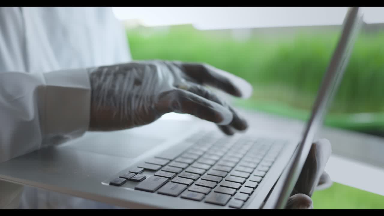 Scientist working on a laptop in a greenhouse