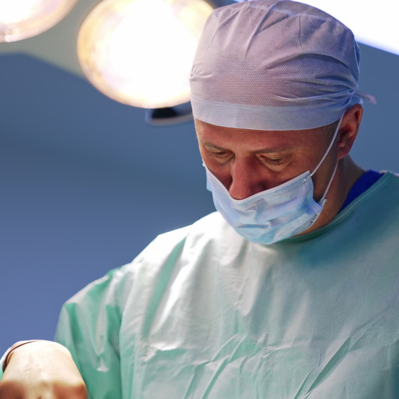 Plastic surgery specialist working under the illumination equipment of surgical room. Low angle view. Blurred background