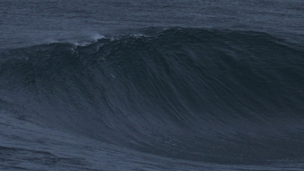 la ola del océano se eleva con agua texturizada rociando niebla de la parte superior a medida que se rompe