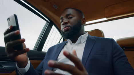 Closeup african man having video call at car. Business man talking phone at car