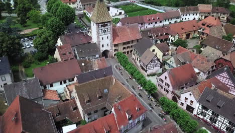 A-rearward-aerial-drone-footage-of-the-clock-tower-while-revealing-the-houses,-the-roads,-and-the-whole-village