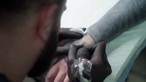 maestro de pintura de tatuaje tatuaje con máquina en el brazo en el salón