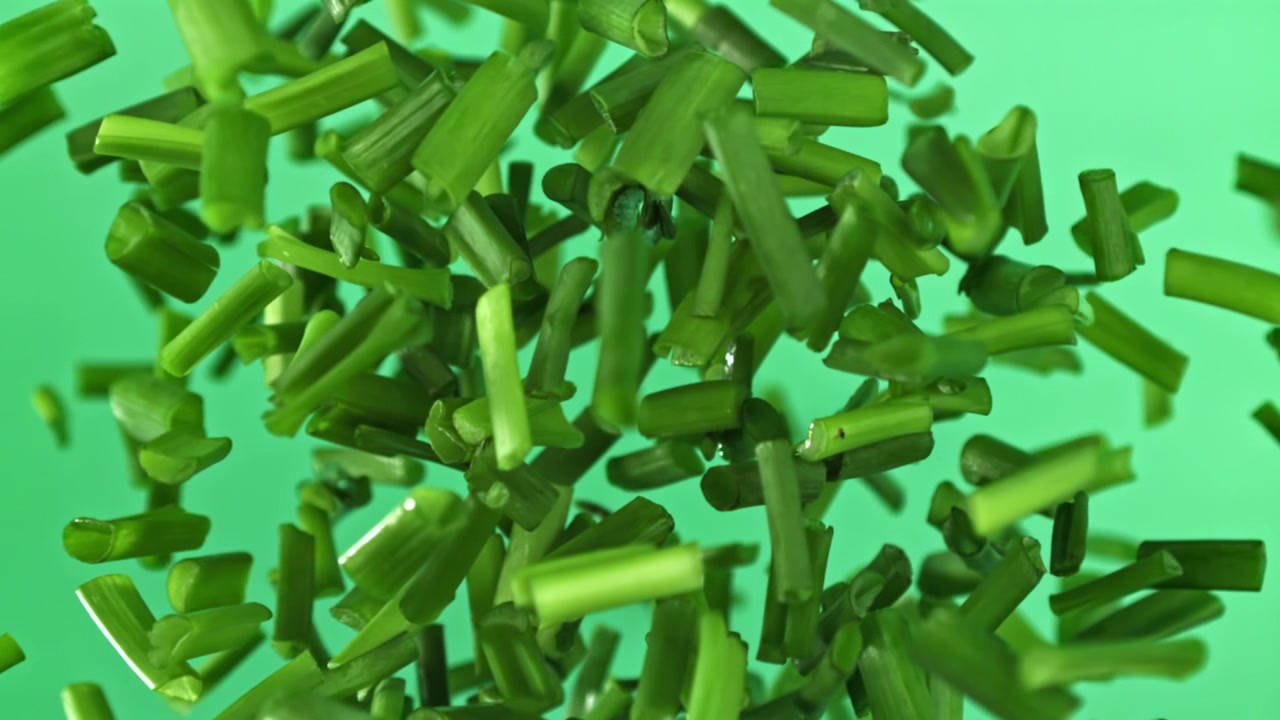 Fresh Chopped Chives Falling in Slow Motion on Green Background