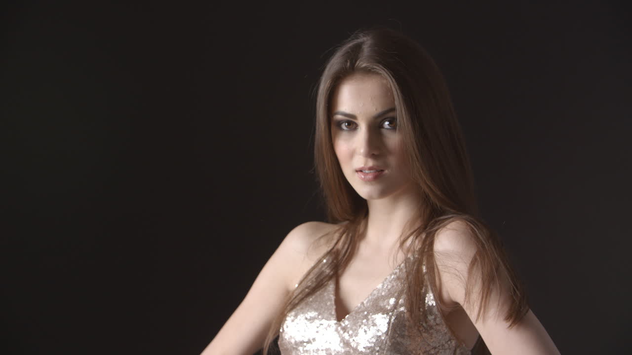 joven en vestido de noche lanza la cabeza y se agita el cabello