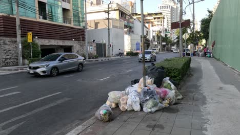 cars driving past piled garbage on urban road