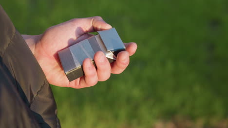 close up of man wearing puffer jacket firmly squeezing and discarding burning cigarette into waste bin beside green grass while making decisive choice to quit smoking in golden sunlight
