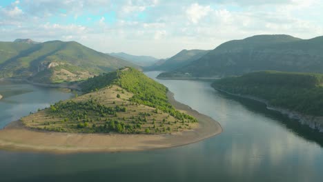 Man-sitting-on-rock-with-amazing-view-over-river-meander,-aerial-shot