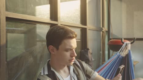 close up of a man using smartphone while sitting in hammock
