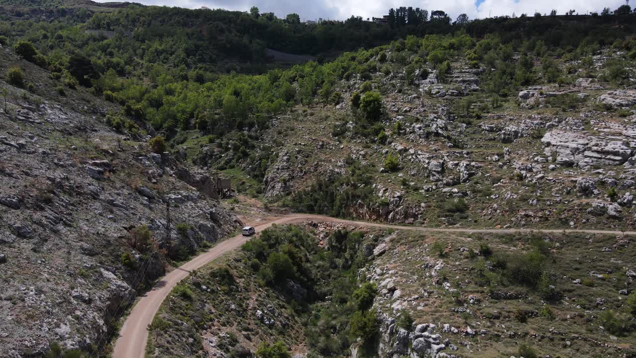 vista aérea de una furgoneta en una carretera rural en el valle de qadisha, líbano, disparo de un dron de seguimiento