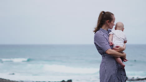 by the sea, the mother lifts her son with laughter-filled tosses into the air, creating a joyful spectacle on the beach. a young family embraces seaside happiness