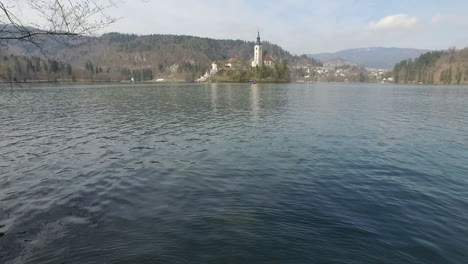 Fliegen-Sie-über-Den-Bleder-See-Und-Sehen-Sie-Die-Insel-Mit-Der-Kleinen-Kirche-In-Der-Mitte-Des-Bleder-Sees,-Slowenien