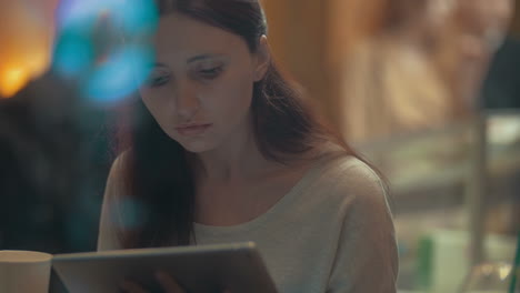 mujer navegando por internet en un pad en un café