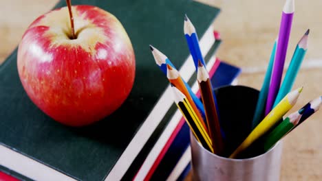 Apple-on-book-stack-with-color-pencil-on-table