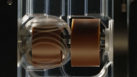 detailed view of a tape mechanism with brown film inside a clear plastic casing
