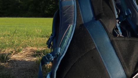 hiker picks up rucksack in countryside close up shot