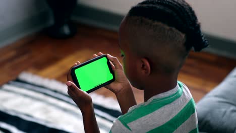 african child holding cellphone with mock-up green screen