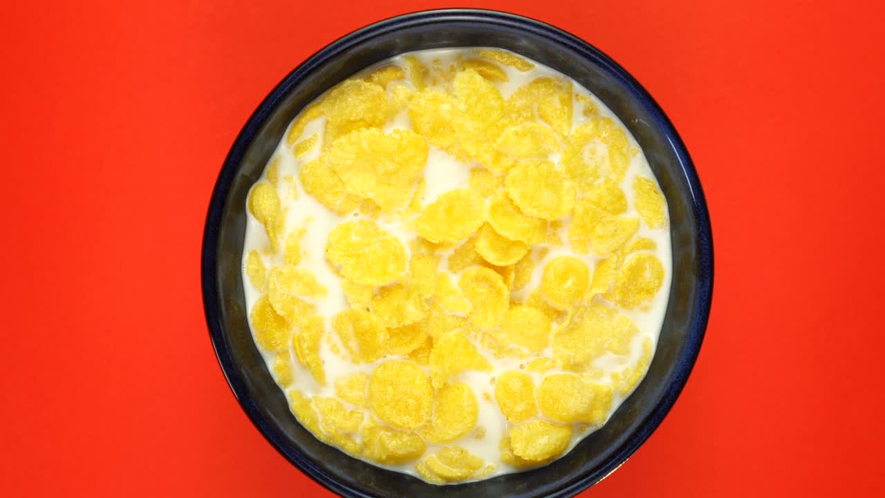 トウモロコシのフレイクが赤い背景でゆっくりと回転しています