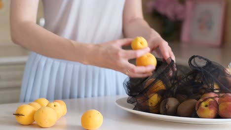 A Woman Stacks Fruit in the Kitchen the Concept of Vegetarianism Eco Bags for Storing Fruit a Woman Stacks Fruit in the Kitchen the Concept of Vegetarianism Eco Bags for Storing Fruit