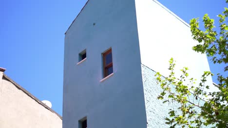 pale blue building with windows against a clear blue sky