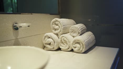 a slow-moving shot captures a beautifully arranged stack of neatly rolled towels in a hotel bathroom, ready for new customers. this presentation reflects luxury and attention to detail in hospitality.