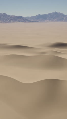 a vast desert landscape with sand dunes and mountains in the distance