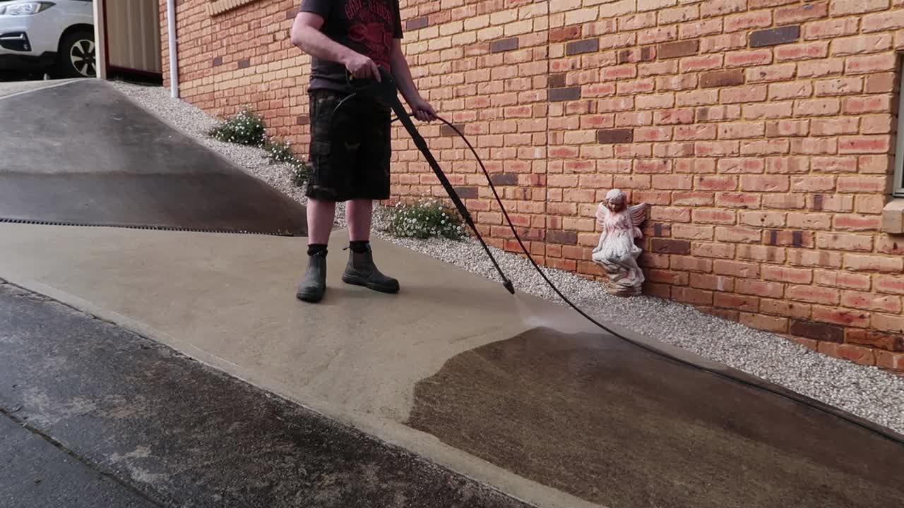 Man wearing boot power washing concrete