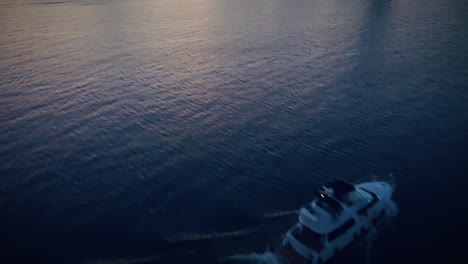 drone flying over a boat on a lake during sunrise