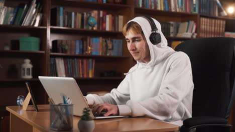 the guy is sitting at the table, obviously playing a computer game