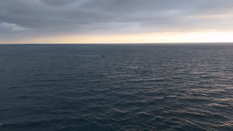 Distant-boat-cruising-on-the-Mediterranean-Sea-near-Genoa,-Italy-during-early-evening,-aerial-view