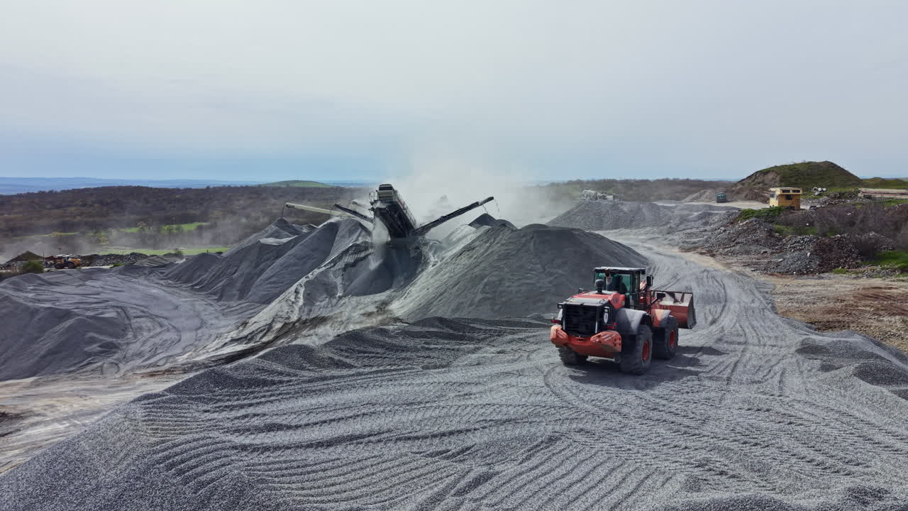 Heavy machinery operates at granite quarry site during daylight hours for stone processing and material extraction