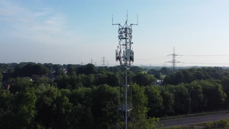 mástil de torre de transmisión de 5g en la campiña británica con vehículos que viajan por la carretera vista aérea de la órbita izquierda del fondo