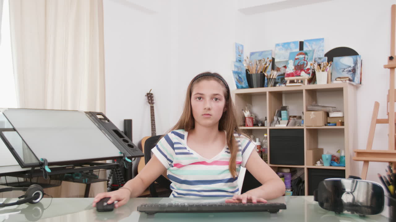 Teenage girl at desk with computer and art supplies