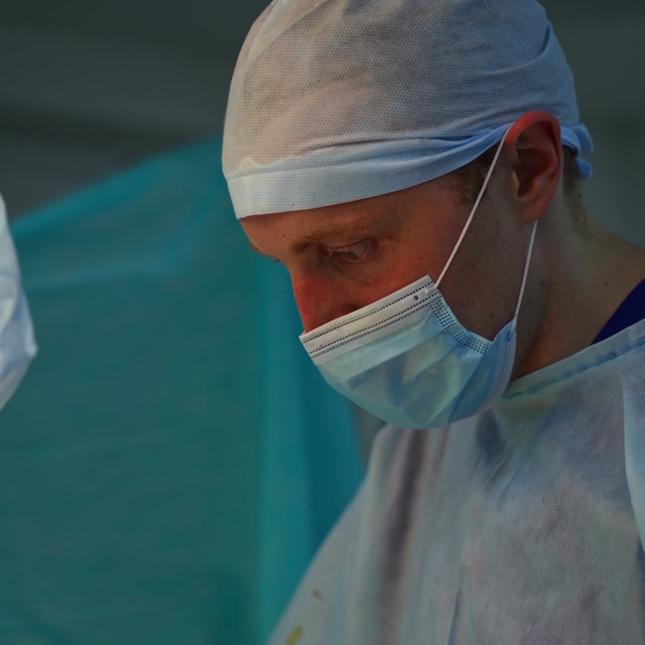 Doctor in medical mask and cap. Operating procedure by medical specialists in hospital. Professional surgeons perform operation. Healthcare concept.