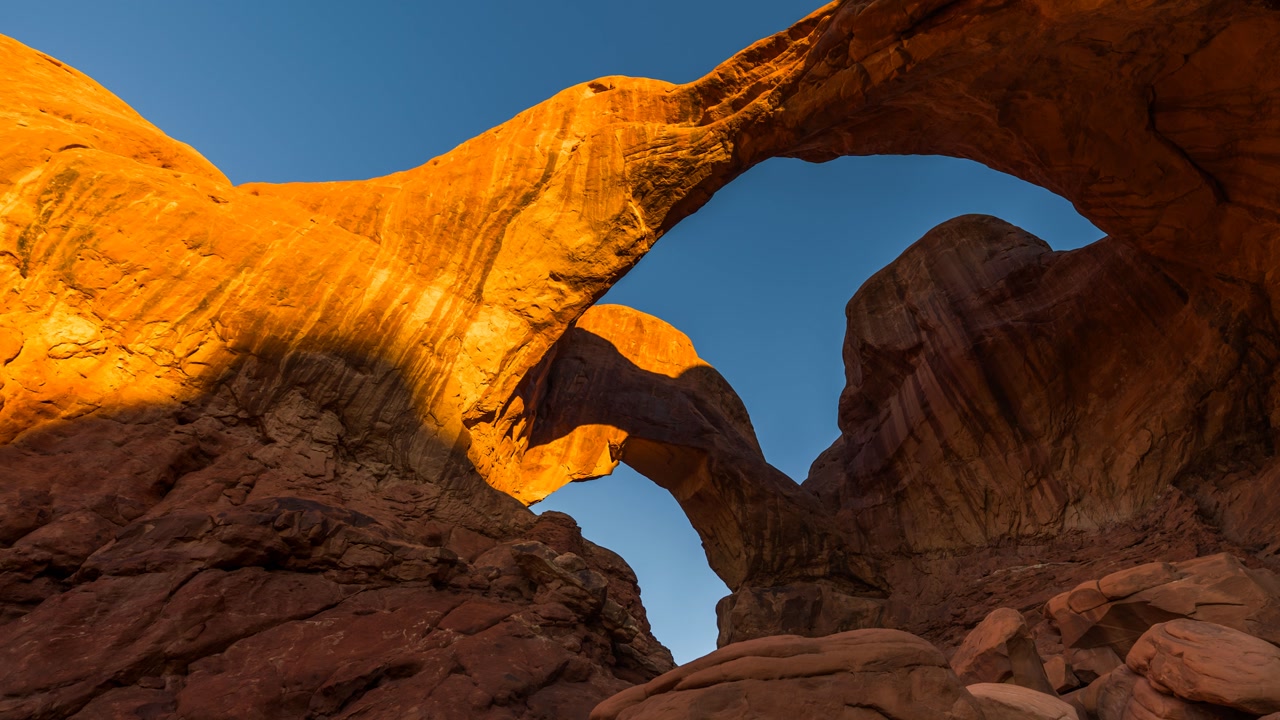 Double Arch sunrise in Arches National Park, golden light hitting rock, Utah, USA. time lapse zoom in