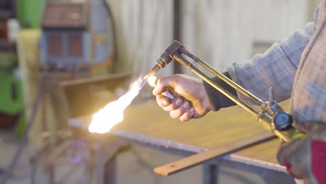 worker lights the fire torch cutter with lighter and adjusts the flame