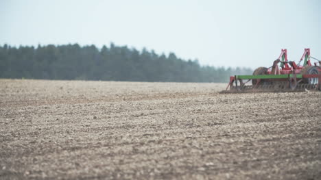 agricultural tractor using harrows while plowing field