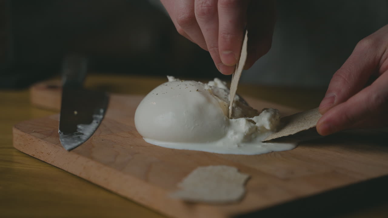 Scooping soft and creamy artisanal Burrata cheese onto a biscuit