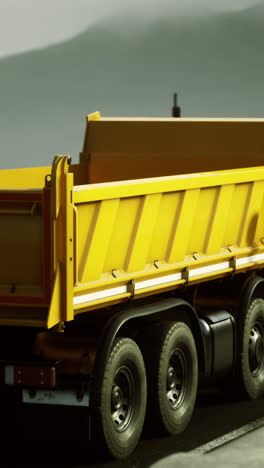yellow dump truck navigating an empty coastal road during golden hour