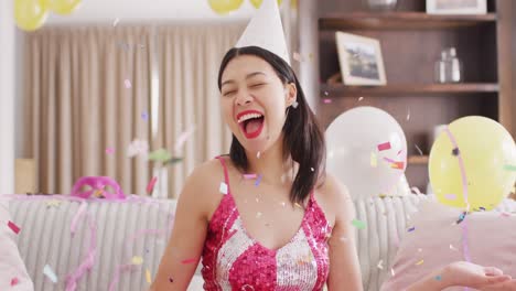 video of smiling biracial woman in party hat and dressed in pink dress