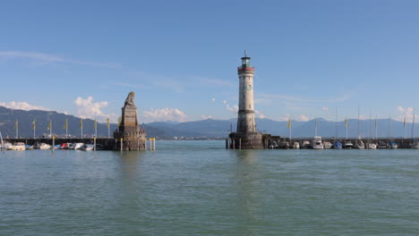 tour boat enters, leaves old lindau harbor past lighthouse, lion statue